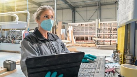 Woman_engineer_operating_on_a_industrial_digital_machine_and_wearing_protective_mask_against_coronavirus