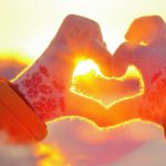 Woman_hands_in_winter_gloves_Heart_symbol_shaped_Lifestyle_and_Feelings_concept_with_sunset_light_nature_on_background