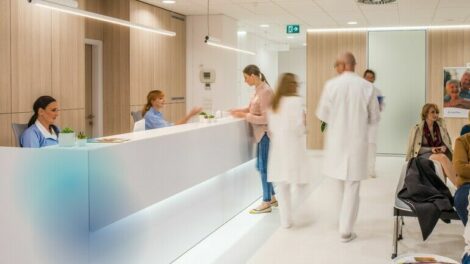 Blurred_motion_of_doctors_walking_in_clinic,_patients_sitting_on_chair.