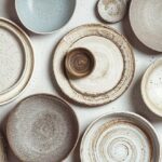 handmade_ceramics,_empty_craft_ceramic_plates_and_bowls_on_light_background,_top_view